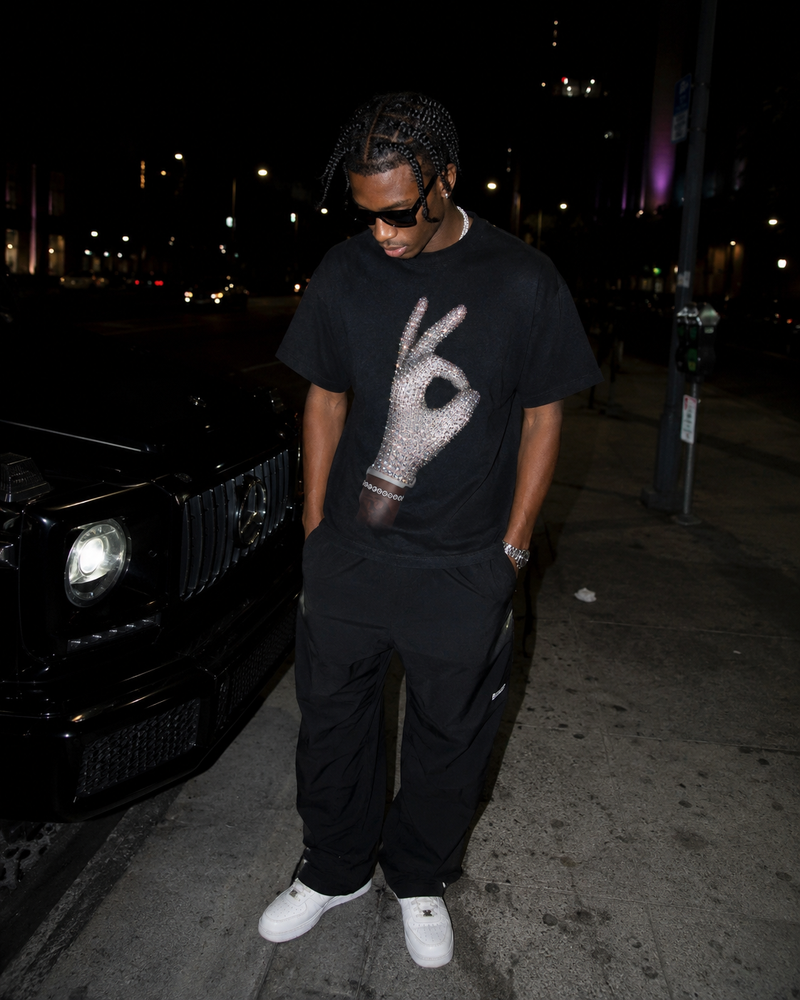 Young man wearing ICEMAN black tee with rhinestone hand print, leaning against G-Wagon at night — Drake ICEMAN album inspired heavyweight boxy streetwear